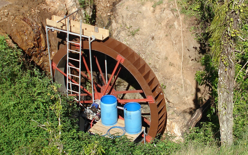 Large 4.6m diameter Yardmaster waterwheel with restricted water diversion from dam to run wheel delivers 28,000 l/day as per client requirement to storage tanks