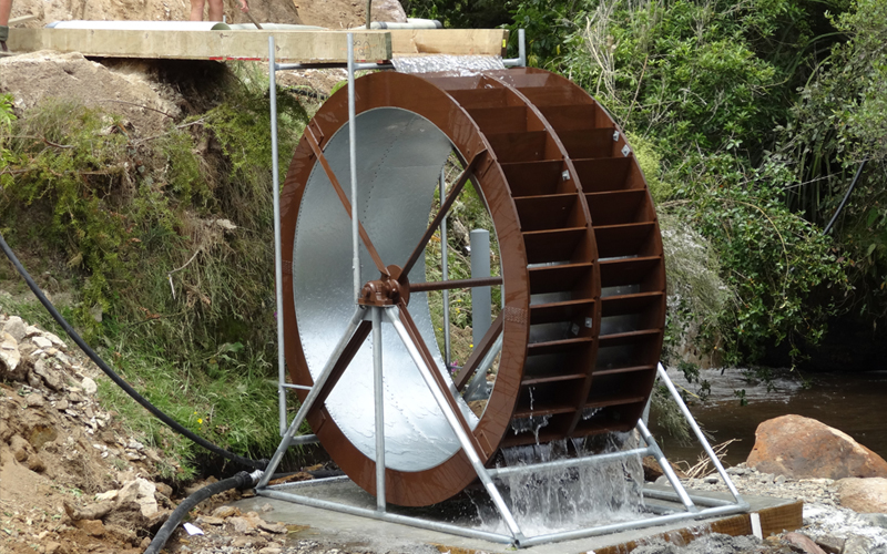 Yardmaster waterwheel run by diverted water drives a water pump delivering water to holding tanks